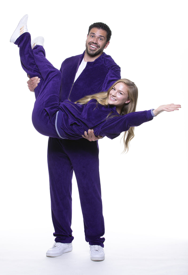 Male model holding female model and they are wearing The Stunner, a retro purple Velomino velour tracksuit that is stylish and comfortable